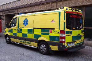 Ambulanz auf der Straße vor einem Ziegelgebäude mit Text geparkt, mit einem Feuerlöscher auf der linken Seite.