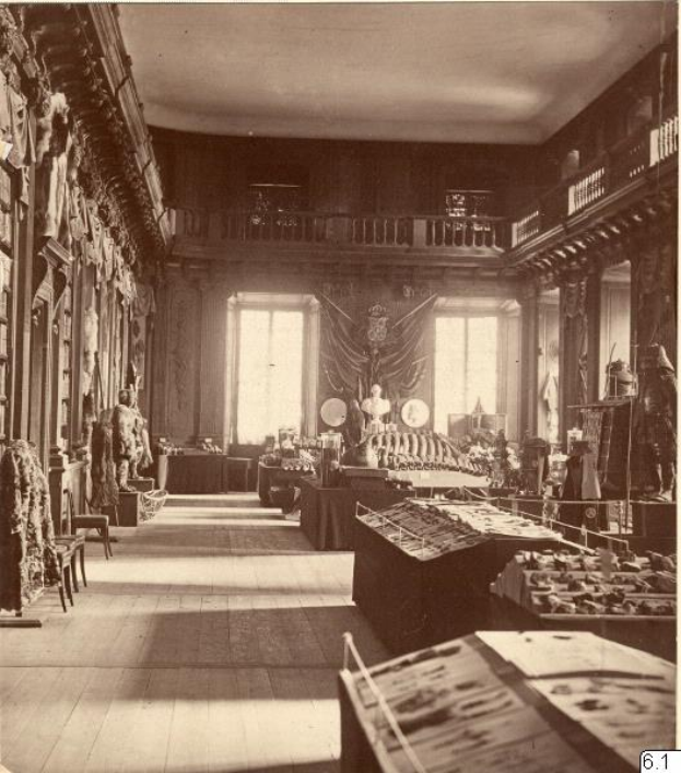 Schwarzes und weißes Foto eines Raums im Museum of Fine Arts, London, mit Tischen, Stühlen, an der Wand hängenden Skulpturen, Fenstern mit Vorhängen und Geländern.