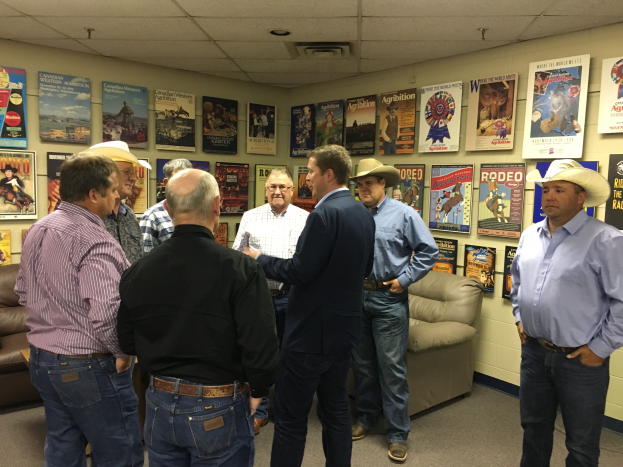 Eine Gruppe von Männern, die in einem Raum mit Sofas, Plakaten an den Wänden und Deckenlampen stehen und sich unterhalten.