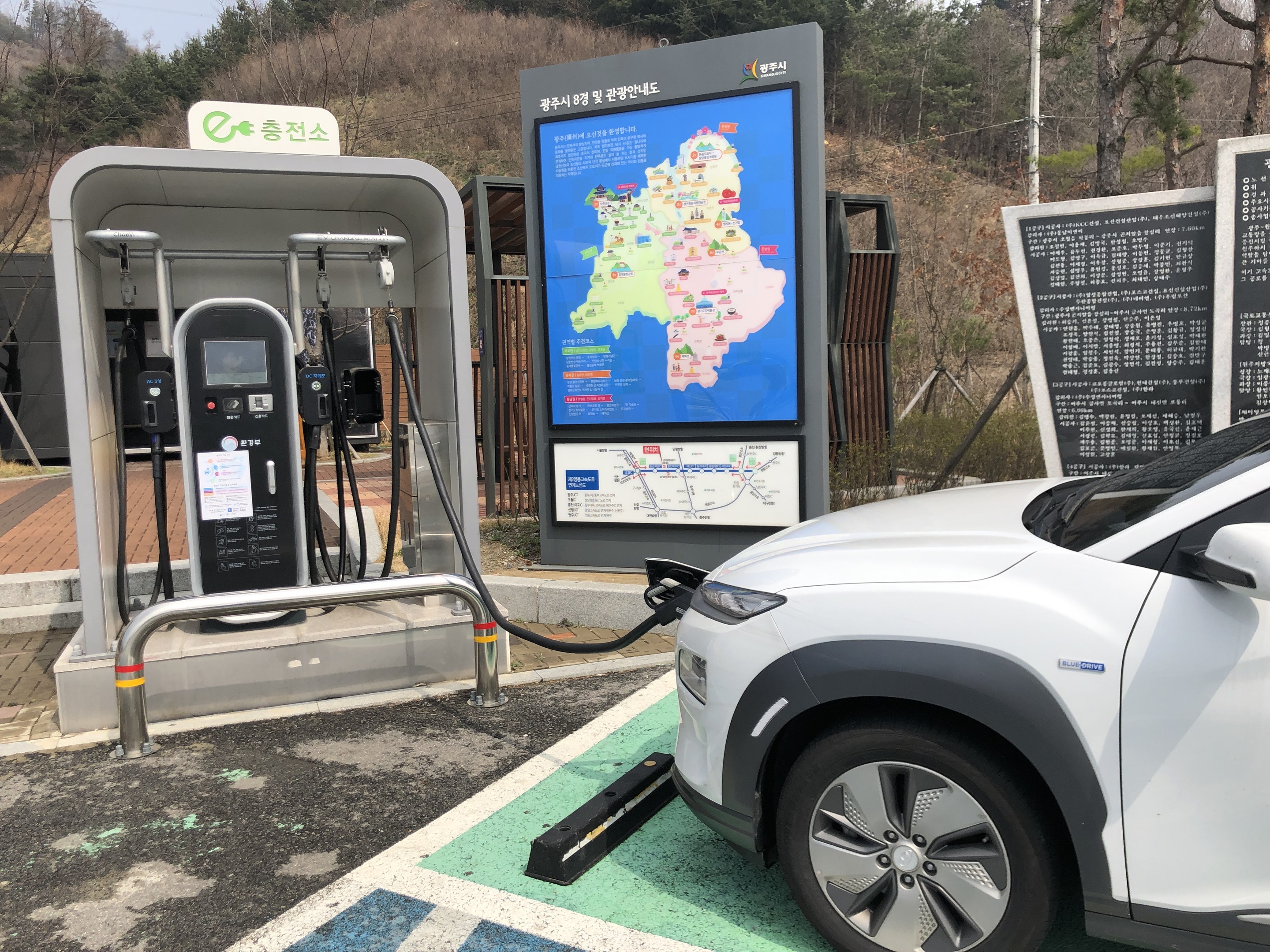 Laden eines Elektroautos an einer Station in Seoul, Südkorea, mit Bäumen und Himmel im Hintergrund.