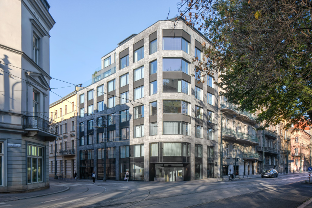 Großes Bürogebäude mit vielen Fenstern, umgeben von Straßeninfrastruktur, Fahrzeugen, Fußgängern, Bäumen und einem bewölkten Himmel, als Sitz der Firmenzentrale identifiziert.