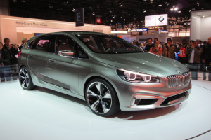 BMW 2er Active Tourer Concept auf der IAA in Frankfurt umgeben von Menschen, die es fotografieren, unter Deckenbeleuchtung mit Texttafeln im Hintergrund.
