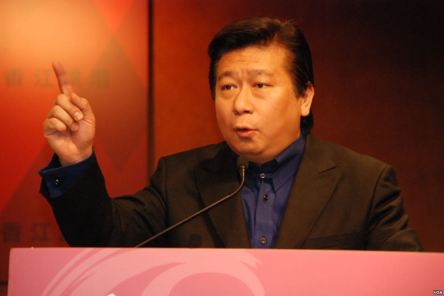 Ein Mann im Anzug und Krawatte hält eine Rede an einem Rednerpult mit einem Mikrofon und hat einen ernsten Gesichtsausdruck.