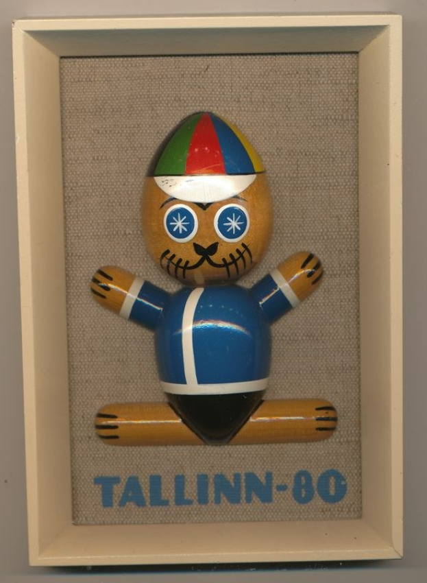 Holzspielzeug namens "Tallinn-80" in einem weißen Rahmen mit einer blauen und roten Mütze, mittig mit lesbarem Text auf dem Körper.