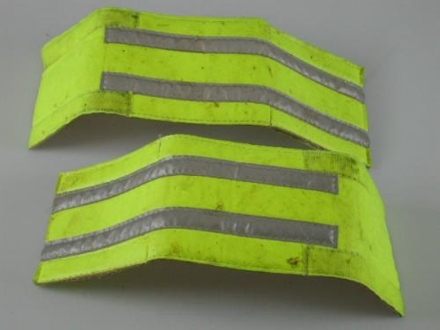 Zwei gelbe reflektierende Sicherheitswesten auf einer weißen Oberfläche, entworfen für hohe Sichtbarkeit.