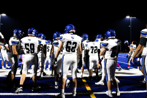 Gruppe von Fußballspielern in Helmen und Stiefeln auf einem Feld unter Flutlicht
