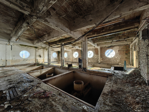Verlassene Gebäudeinterieur im Chernobyl-Ausschlussgebiet mit verstreuten Trümmern, freiliegenden Wänden, Decke und strukturellen Elementen.