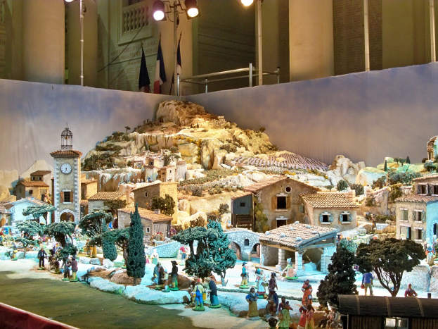 Eine detaillierte Museumsausstellung einer Krippe mit Figuren, Strukturen und beleuchteten Elementen in einer festlichen Umgebung.