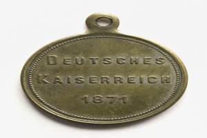 Eine Bronzemedaille mit der Aufschrift "Deutsches Kaiserreich 1871" auf einem weißen Hintergrund.