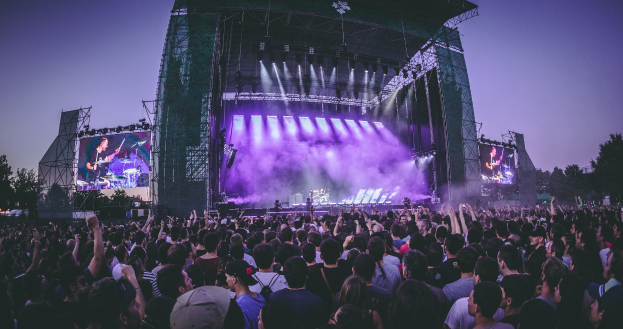 Schwarzes und weißes Foto von Wagners Opernhaus in Bayreuth, mit ein paar Menschen vor dem Gebäude stehend, umgeben von Bäumen und einem klaren Himmel, mit Text unten.
