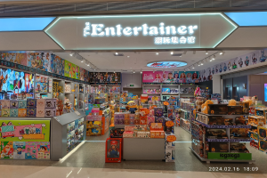 Ein hell erleuchteter Spielwarenladen namens "Entertainer" mit Regalen und Bodendisplay voller verschiedener Spielzeuge und Deckenbeleuchtung.