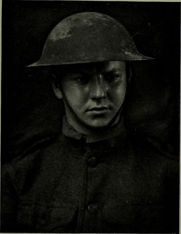 Schwarzes und weißes Foto eines Mannes in dunkler Uniform mit Schirmmütze, Helm und ernster Miene, der in die Ferne schaut.