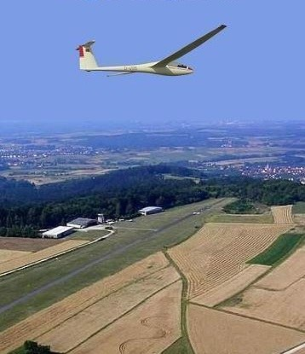 Segelflugzeug über einem Feld mit Bäumen und Gebäuden im Hintergrund, mit Text oben auf dem Bild.