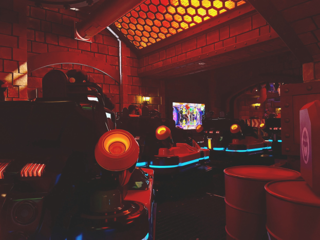 Ein hell erleuchteter Raum voller verschiedener Arcade-Videospielautomaten, Bildschirme und anderer Ausrüstung, der eine lebendige Atmosphäre schafft.