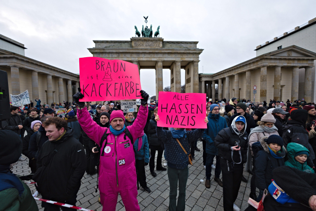 Gruppe von Demonstranten versammelt sich vor dem Brandenburger Tor in Berlin und hält Schilder gegen die Anti-Nazi-Bewegung der deutschen Regierung.