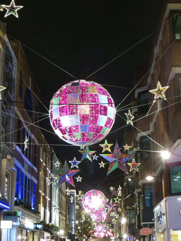 Eine festlich geschmückte Stra├če mit einer gro├čen Diskokugel und beleuchteten D├Ąchern.