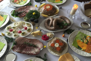 Ein traditionelles deutsches Osteressen auf einem Tisch mit verschiedenen Gerichten, Besteck, Gläsern, Kerzen und Stühlen.