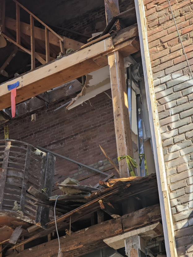 Ein teilweise abgerissenes Gebäude mit verstreuten Holzplanken und Schutt, mit zerbrochenen Fenstern und Türen.